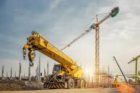 Rough-terrain crane and a tower crane on a construction site at sunset