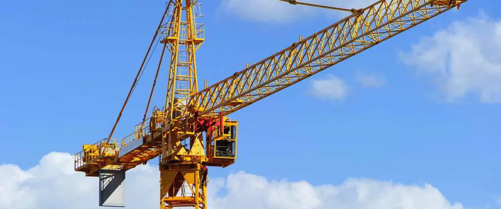 Yellow tower crane jib and operator cab against a blue sky