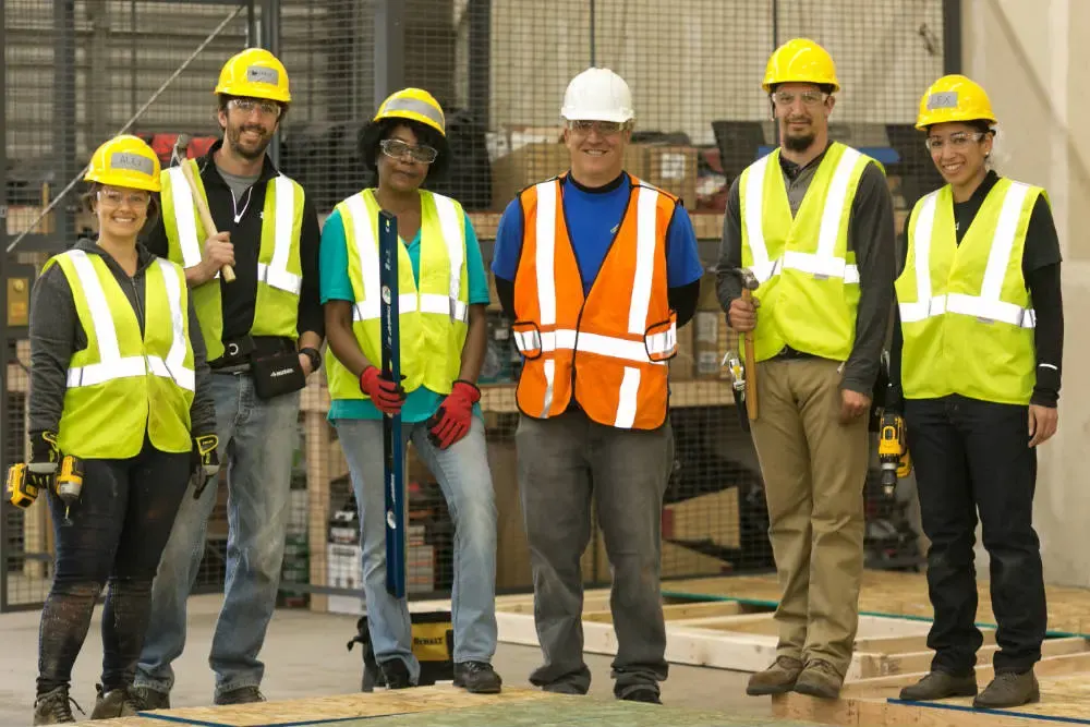 A construction crew in hard hats and high-visibility vests standing together on a job site