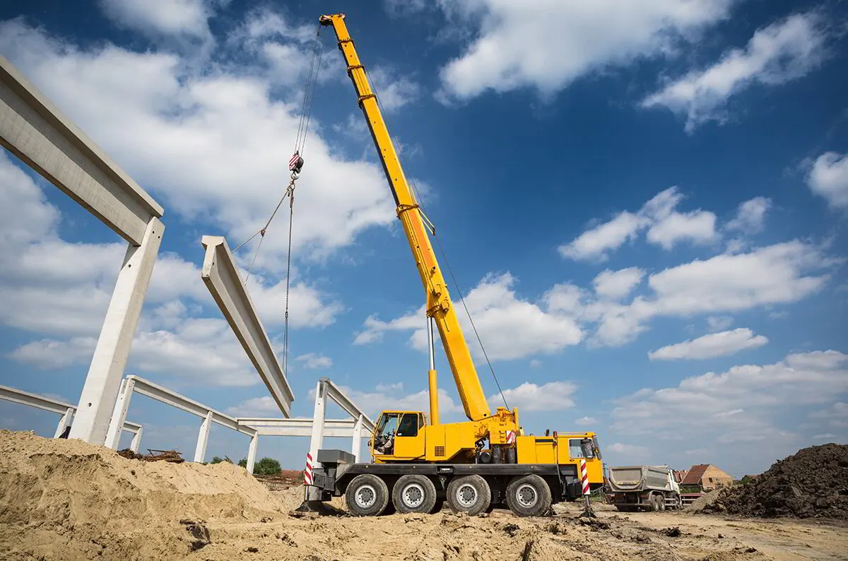 Mobile crane with an extended telescopic boom set up beside a building